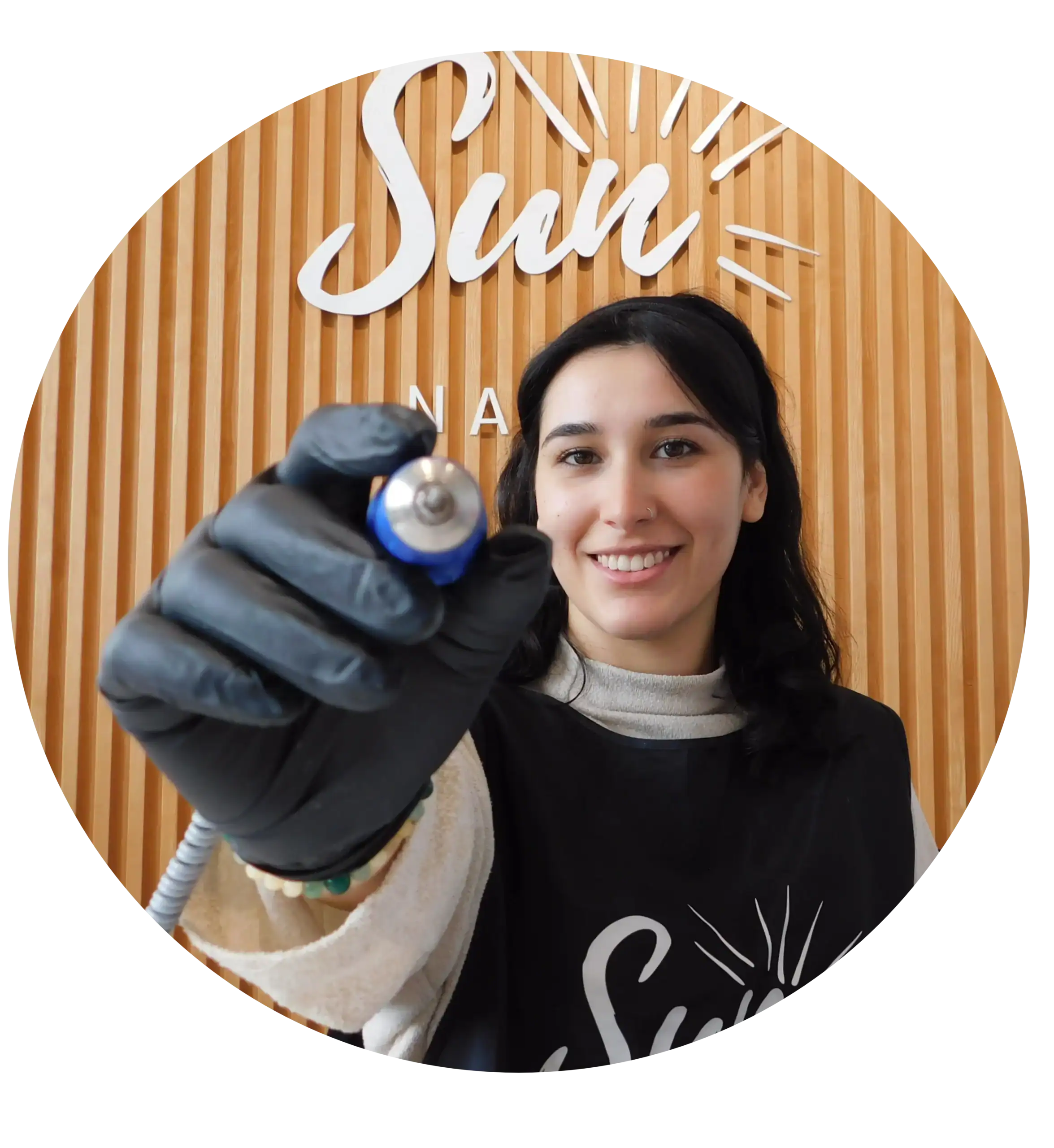 Manicurista de Sun Nails sonriendo y mostrando herramienta de trabajo en un entorno profesional y cálido